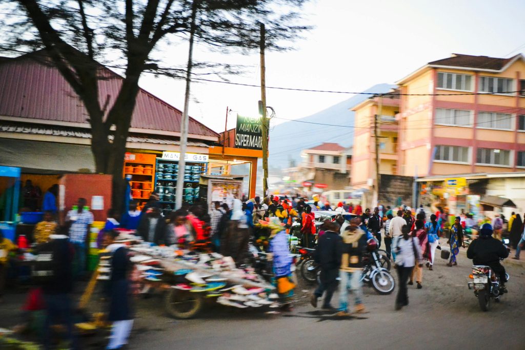 Bustling street market in Arusha, Tanzania with diverse crowd, shops, and vibrant urban life.